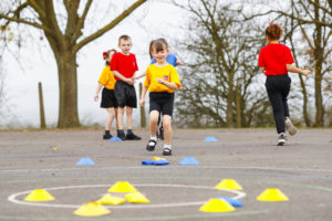 A small group of pupils can be seen participating in outdoor exercise during a PE lesson.