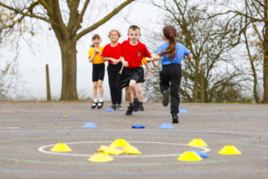 A small group of pupils can be seen running and participating in outdoor exercise during a PE lesson.